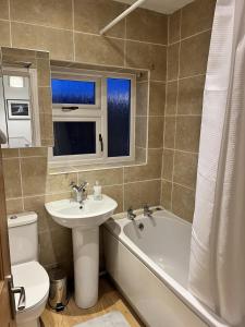 ein Badezimmer mit einem Waschbecken, einer Badewanne und einem WC in der Unterkunft Impeccable 3-Bed House in Nottingham in Nottingham