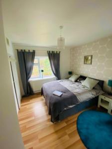 Impeccable 3-Bed House in Nottingham في نوتينغهام: غرفة نوم بسرير وسجادة زرقاء ونافذة