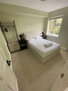 a bedroom with a white bed and a window at Newly refurbished apartment, near station & river in London