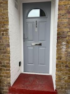 een witte deur met een raam op een stenen muur bij Newly refurbished apartment, near station & river in Londen