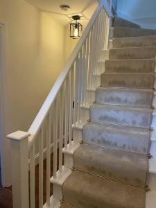 a stairway with white stairs and a light fixture at Newly refurbished apartment, near station & river in London