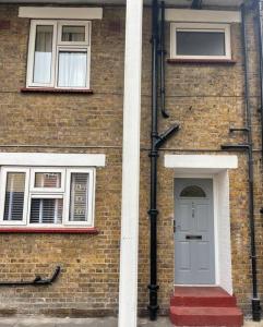 ceglany budynek z drzwiami i dwoma oknami w obiekcie Newly refurbished apartment, near station & river w Londynie