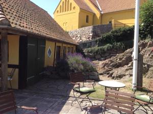 un patio con sillas, una mesa y un edificio en Hotel Klostergaarden, en Allinge