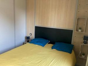 1 dormitorio con 1 cama con 2 almohadas azules en COTTAGE 4/5 pers en Jullouville-les-Pins