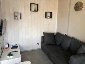 - un salon avec un canapé et un réveil sur le mur dans l'établissement COTTAGE 4/5 pers, à Jullouville