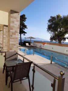 a balcony with a table and chairs next to a swimming pool at Melydron Apartments in Preveza