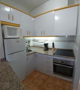 uma pequena cozinha com armários brancos e um lavatório em Relax, mar y sol em Torrevieja