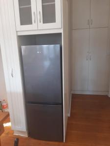 a stainless steel refrigerator in a kitchen with white cabinets at Fun-filled, cosy family home in Gqeberha