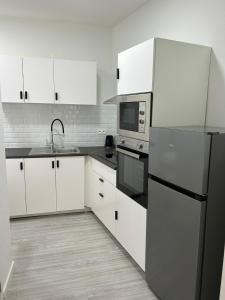 La cuisine est équipée de placards blancs et d'un réfrigérateur noir. dans l'établissement Immeuble au cœur de Bruxelles : Vivez l'Expérience Unique de la Rue Verbist, à Bruxelles