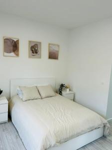 1 dormitorio blanco con 1 cama y 3 cuadros en la pared en Immeuble au cœur de Bruxelles : Vivez l'Expérience Unique de la Rue Verbist en Bruselas