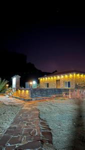 a stone building with lights on it at night at مزرعة القمة in Mogayra