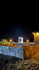 a stone wall at night with a building in the background at مزرعة القمة in Mogayra