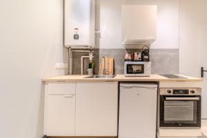 a kitchen with white cabinets and a microwave at Résidence Les Halles charmant 1 chambre Bocuse Part Dieu in Lyon