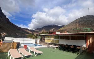 a house with chairs and a swimming pool and mountains at Las Medinas Apartamentos in Las Palmas de Gran Canaria