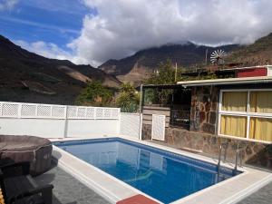 a swimming pool in front of a house with a mountain at Las Medinas Apartamentos in Las Palmas de Gran Canaria