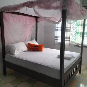 a bedroom with a four poster bed with an orange pillow at Aurelia Nelly in Ukunda