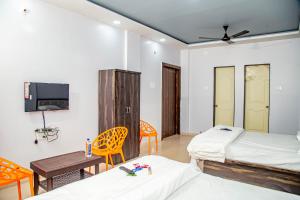 Habitación con 2 camas, mesa y TV. en Raigad Srushti, en Alībāg