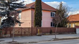 una casa rosa con una valla de madera en FeriAna Residence, en Miercurea-Ciuc