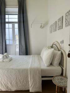 a bedroom with a bed with white sheets and a window at Ti Maria Guest House in Faro