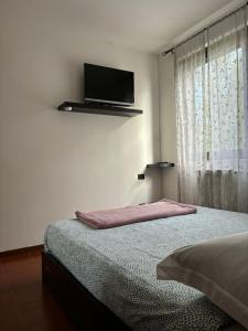 - une chambre avec un lit et une télévision murale à écran plat dans l'établissement La casa di Jacopo a Fiumicino, à Maccarese