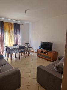 - un salon avec un canapé, une télévision et une table dans l'établissement Condomínio palma azul II, à Praia