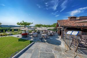 un patio con tavoli, sedie e ombrelloni di Relais & Spa Castello di Casiglio a Erba