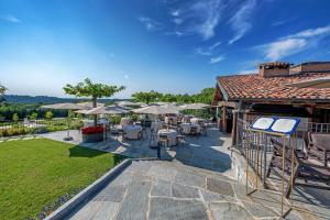 un patio con mesas, sillas y sombrillas en Relais & Spa Castello di Casiglio, en Erba