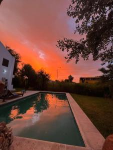 a swimming pool with a sunset in the background at Casa quinta WhiteHouse in San José del Rincón