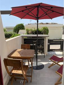 een tafel en stoelen en een parasol op een patio bij Cap d'Agde Naturiste Port Nature 2 in Cap d'Agde