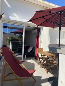 阿格德角的住宿－Cap d'Agde Naturiste Port Nature 2，庭院配有桌椅和遮阳伞。