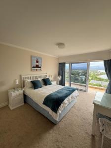 1 dormitorio con cama grande y ventana grande en Holiday Villa with stunning views near beach., en Plettenberg Bay