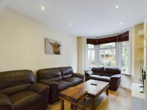 a living room with leather couches and a coffee table at Cosy 4 bedroom, 3 bathroom home - 5 mins from East Croydon station in South Norwood