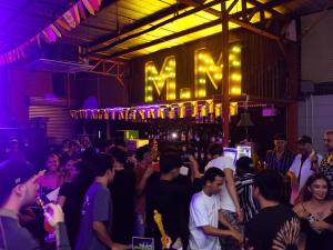 a crowd of people standing in a bar with a neon sign at Mad Monkey Cebu City in Cebu City