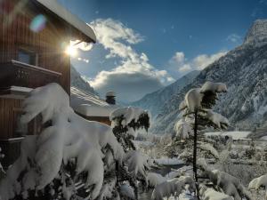 dom pokryty śniegiem obok góry w obiekcie Hotel Astoria w mieście Courmayeur