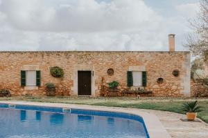a stone house with a swimming pool in front of it at Finca Es Llobets - Adults Only in S'Estanyol de Migjorn