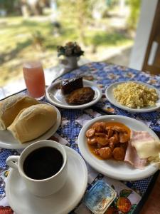 a table with plates of food and a cup of coffee at Alfa Mar Pousada in Abraão