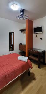 Dormitorio con cama, escritorio y TV en Hostal El Candelabro, en Pisco