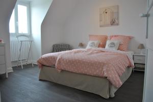 Schlafzimmer mit einem Bett mit rosa und weißer Bettwäsche in der Unterkunft Villa DUXCAAR Avel Mor in Guissény
