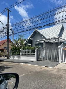 a white house with a white picket fence at Naka Cozy House in Phuket City in Ban Rangeng