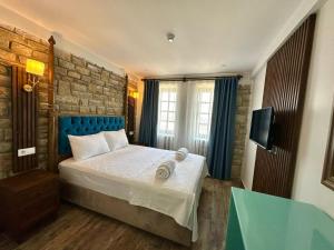 a bedroom with a bed with a blue headboard and a television at İLİA BUTİK OTEL in Eceabat