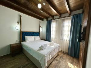 a bedroom with a bed with blue curtains and a window at İLİA BUTİK OTEL in Eceabat