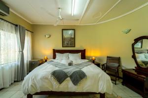 a bedroom with a large bed and a mirror at Room in Villa - Zambezi Family Lodge - Lion Room in Victoria Falls