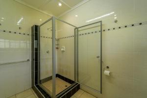 um chuveiro numa casa de banho com uma porta de vidro em Room in Villa - Zambezi Family Lodge - Lion Room em Victoria Falls