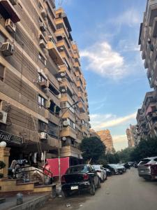 a city street with cars parked next to a tall building at شقة مفروشة مدينة نصر in Cairo