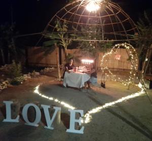 Una pareja sentada en una mesa con un signo de amor por la noche en Hotel Shaddai en Villavieja