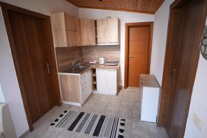 Elle comprend une petite cuisine avec des placards en bois et un évier. dans l'établissement Grandpa House-Attic App 4, à Tirana