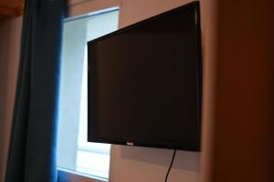 Elle comprend une télévision à écran plat suspendue sur un mur à côté d'une fenêtre. dans l'établissement Near Center Apartments 4, à Tirana