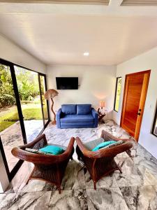 a living room with a blue couch and two chairs at Luxury Villas Arenal in Fortuna