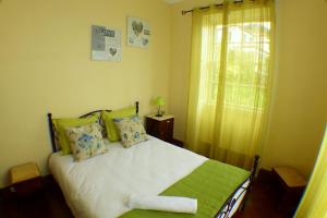um quarto com uma cama com lençóis verdes e brancos e uma janela em Casa da Avó Benvinda no Funchal