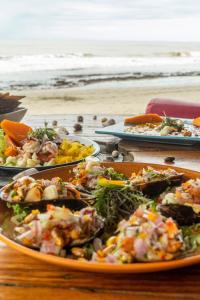 - une table avec des assiettes de nourriture sur la plage dans l'établissement Wiracocha Hostal Máncora - Surf Camp, à Máncora